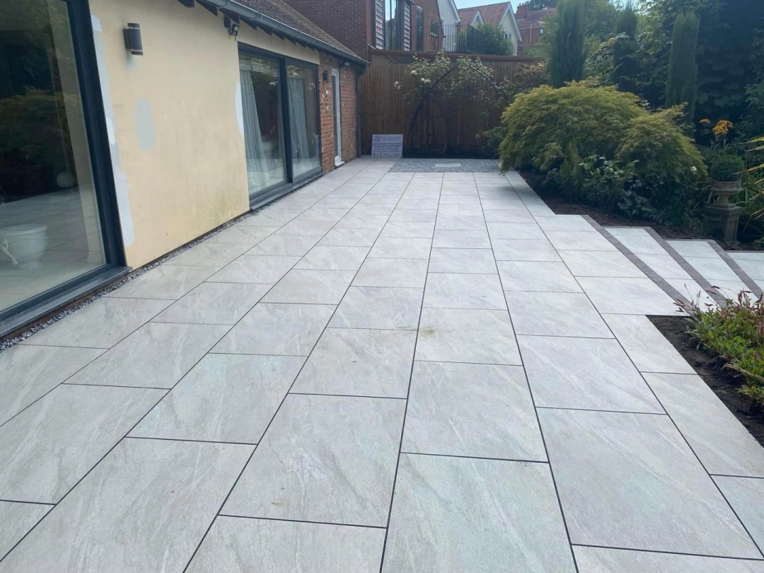 Large porcelain patio installed beside a home by Axtell Landscaping